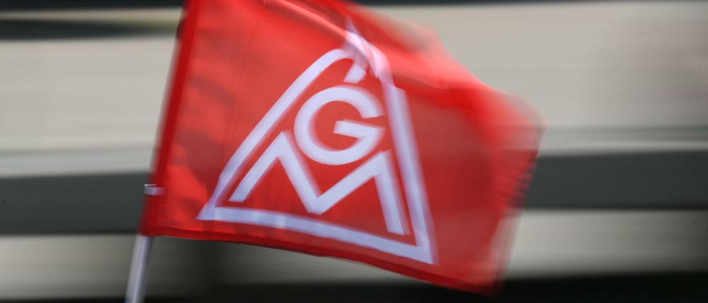 Eine IG-Metall-Flagge spiegelt sich in einem Fahrzeugdach. Die größte deutsche Gewerkschaft ist am stärksten in der Autoindustrie - und hier steht ein tiefer Wandel bevor. 