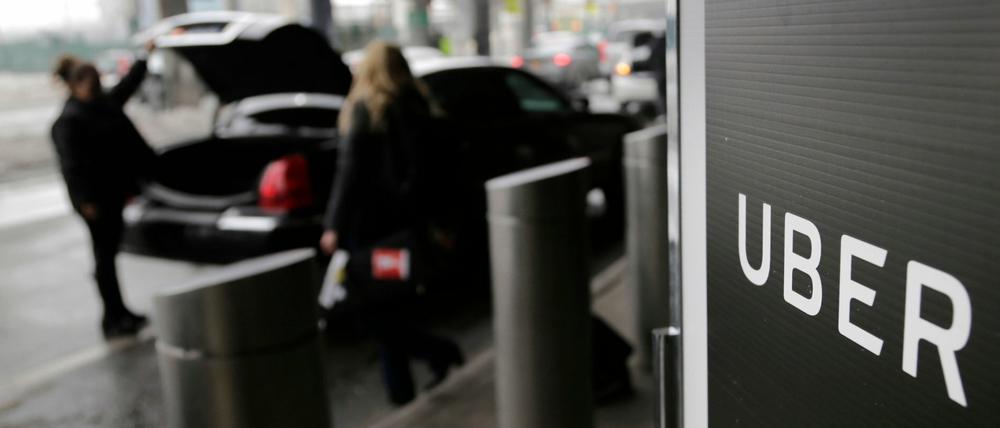 Ein Schild mit dem Logo des amerikanischen Dienstleistungsunternehmens Uber steht am Abholpunkt von Uber auf dem LaGuardia-Flughafen (Symbolbild).
