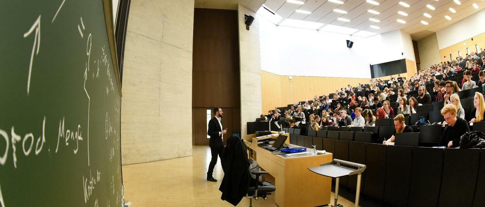 Ein Dozent steht vor Studierenden in einem Hörsaal.