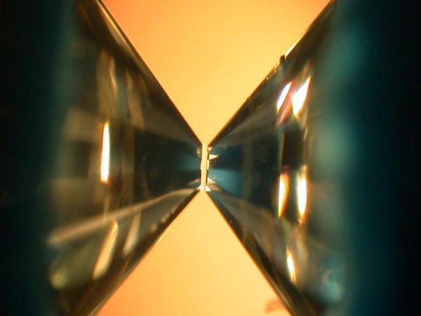 Kleine Fläche, großer Druck. Mikroskopaufnahme einer Diamantstempelzelle. Dort werden die Spitzen von zwei Brillianten so aufeinander gerichtet, dass ein winziger Probenraum entsteht. Durch die kleine Fläche entsteht ein gewaltiger Druck, der dem des Erdkerns entsprechen kann. 