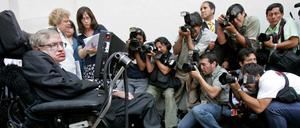 Stephen Hawking bei einer Pressekonferenz, Fotografen richten ihre Kameras auf ihn.