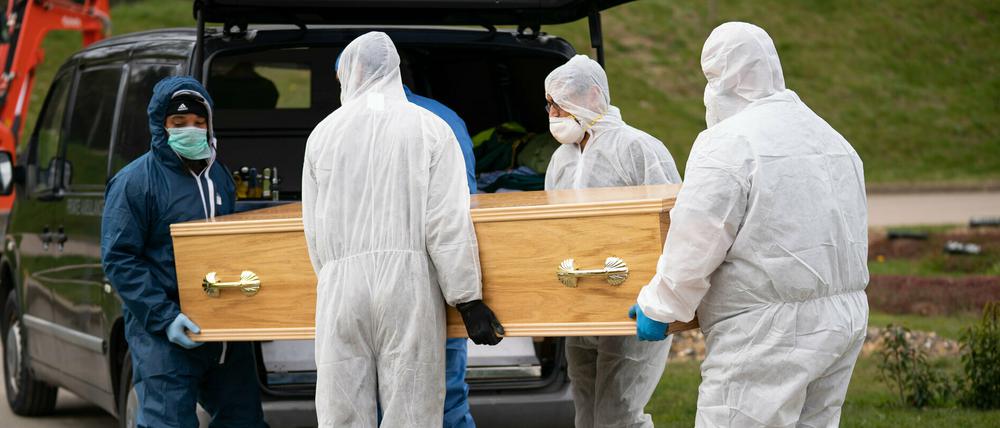 Sargträger in Schutzanzügen bringen am 03.04.2020 einen mit dem Coronaviurs infizierten Toten zu einem Leichenwagen in britischen Chislehurst.