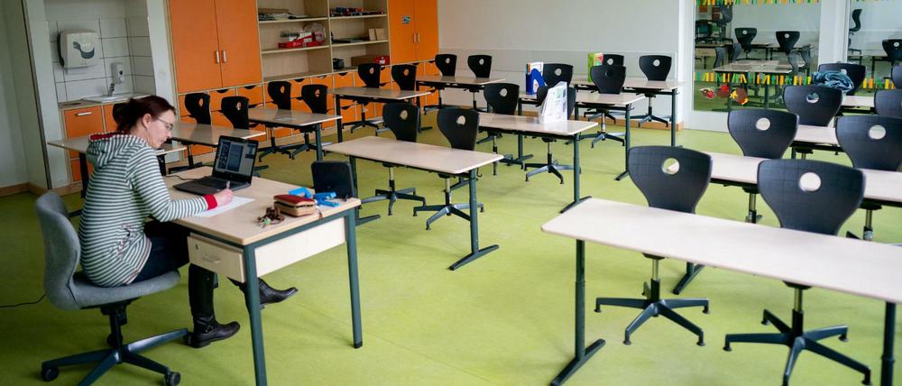Karin Bitter, Lehrerin an der Comenius Grundschule in Oranienburg, sitzt in ihrem leeren Klassenzimmer vor einem Laptop.