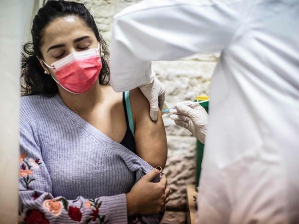 Israel, Jerusalem. Eine Frau erhält eine Impfung gegen das Coronavirus von einem medizinischen Mitarbeiter in einem Impfzentrum.