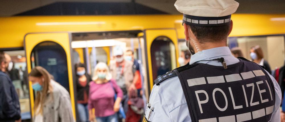 Polizeibeamte kontrollieren an einer Haltestelle im öffentlichen Nahverkehr die Einhaltung der Maskenpflicht