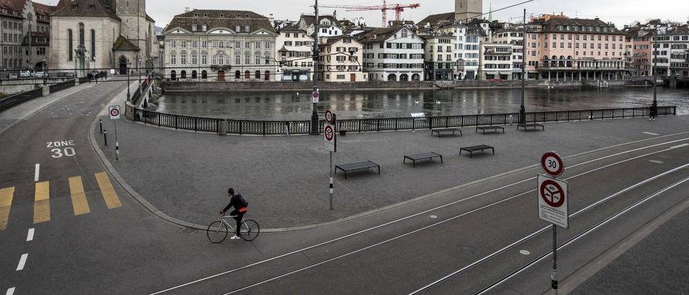 Ein Radfahrer fährt einsam durch die leeren Straßen von Zürich.
