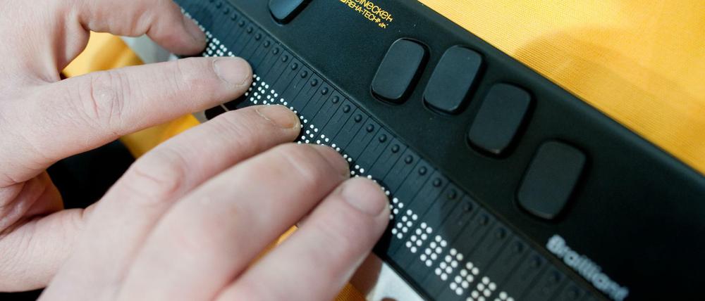 Eine Braillezeile zeigt den Bildschirminhalt am Computer in Punktschrift an. Das Bild zeigt, wie der Inhalt dann mit den Fingerkuppen ertastet wird.