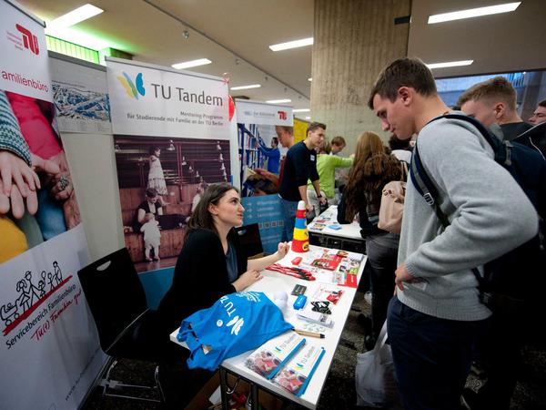 Eine Infomesse für Studienanfänger an der TU Berlin im Jahr 2017. Zu sehen ist ein junger Mann im Gespräch an einem Infostand.