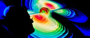 Der Schattenriss eines Mannes ist vor der Visualisierung der Gravitationswellen zu sehen.