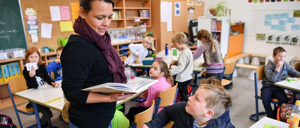Eine Lehrerin liest ihren Drittklässlern aus einem Buch vor.