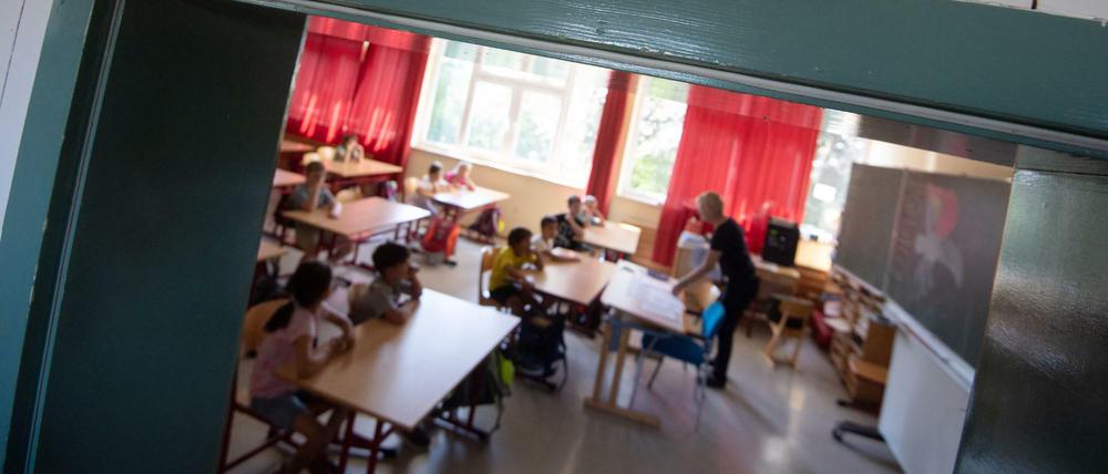 Blick durch die Tür in ein Klassenzimmer, in der eine junge Lehrerin unterrichtet.