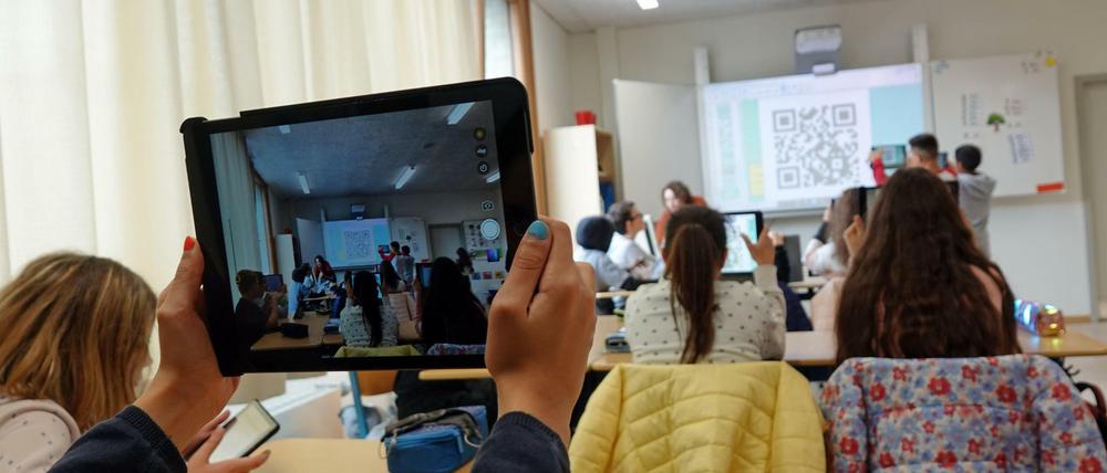 Eine Schülerin hält ihr neues iPad in einem Klassenraum hoch.