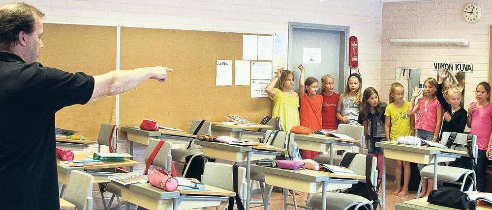 In einer finnischen Schule ruft ein Lehrer Schüler auf, die im Klassenzimmer an der hinteren Wand stehen und sich melden.