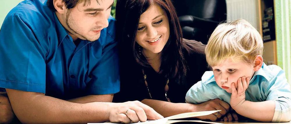Ein Mann und eine Frau betrachten gemeinsam mit einem kleinen Kind ein Buch.