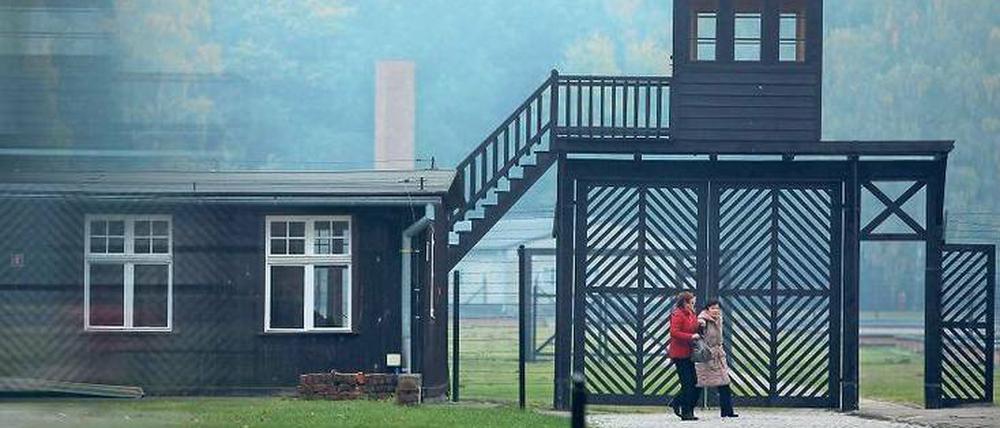 Vor dem Eingangstor eines ehemaligen deutschen Konzentrationslagers in Polen gehen zwei Frauen einen Weg entlang.