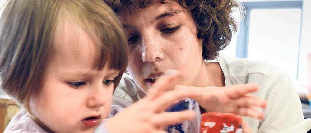 Eine junge Frau und ein kleines Mädchen kleckern Farbe auf eine Glasscheibe.