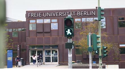 Grüne Fußgängerampel vor einem Hauptgebäude der Freien Universität Berlin.