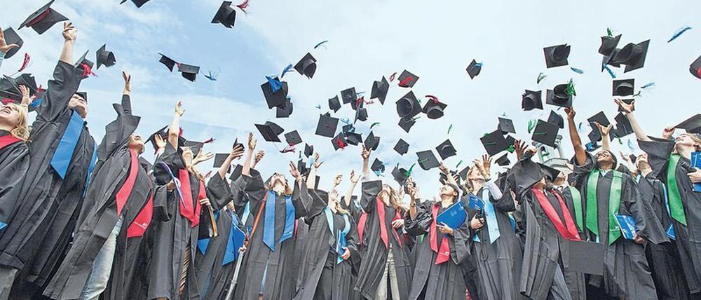 Bei einer Absolventenfeier an der Universität Bonn werfen junge Frauen und Männer ihre "Doktorhüte" in die Luft.