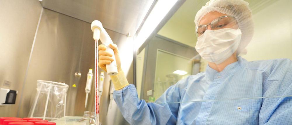 Eine Labormitarbeiterin füllt eine Flüssigkeit mit einer Pipette in Kunststoffröhrchen.