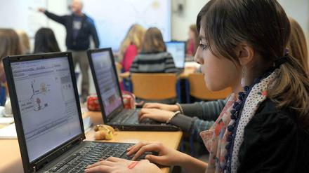 Jugendliche arbeiten in einem Klassenzimmer an Laptops.