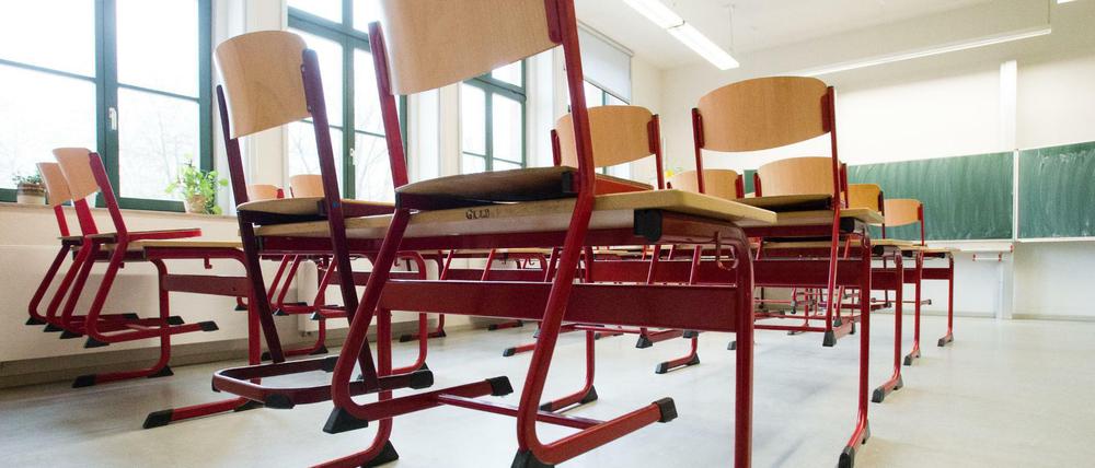 In einem leeren Klassenzimmer stehen Stühle auf den Tischen.