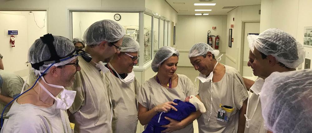 Im Krankenhaus in Sao Paulo umringt ein Ärzteteam das Neugeborene, das in eine blaue Decke gewickelt ist. 