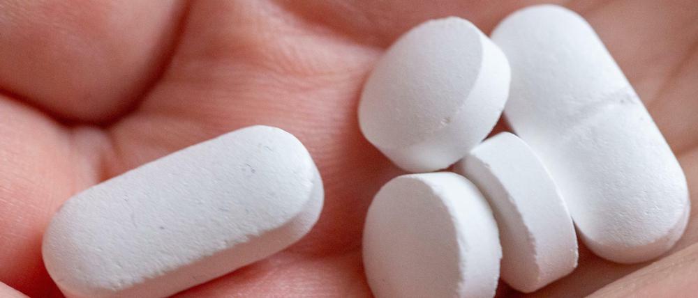 Eine Person hält Tabletten und Vitaminpräparate von Calcium, Vitamin D und Magnesium in der Hand