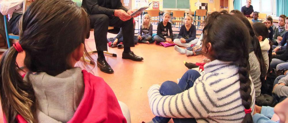 Kinder sitzen beim Vorlesetag im Halbkreis auf dem Boden und hören zu.