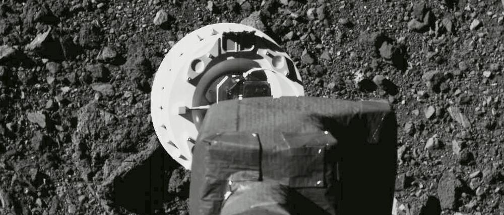 Ein Roboterarm saugt eine Probe von einer geröllbedeckten Oberfläche auf.