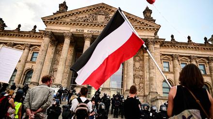 Ein Teilnehmer einer Kundgebung gegen die Corona-Maßnahmen schwenkt eine Reichsflagge vor dem Reichstagsgebäude.
