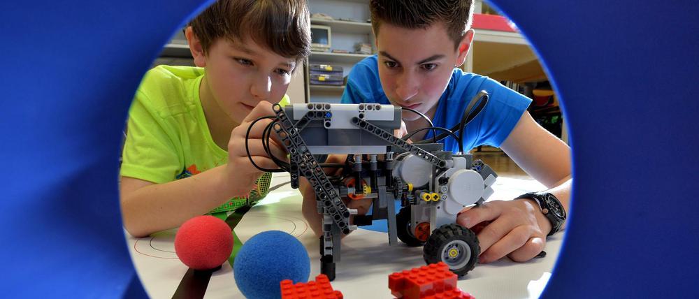 Zwei Schüler bauen einen technischen Apparat aus Legosteinen.