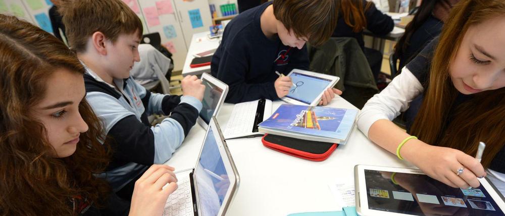 In einer Schulklasse arbeiten Kinder an Tablet-Computern.