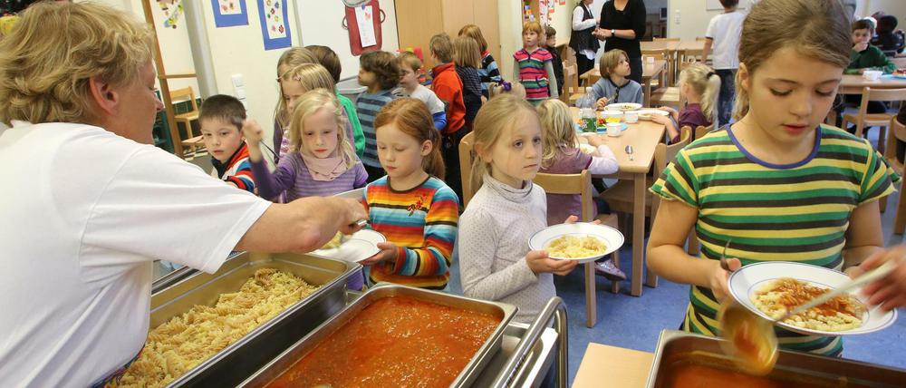 In der Kantine einer Grundschule bedienen sich Kinder mit Nudeln und Tomatensoße.