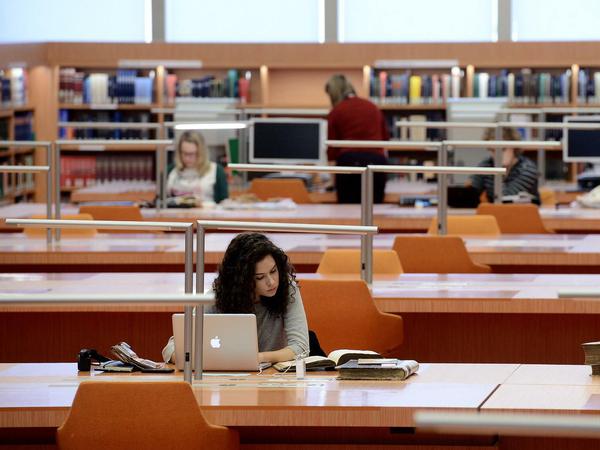 Eine junge Wissenschaftlerin sitzt in einem Lesesaal der Staatsbibliothek zu Berlin an ihrem Laptop.