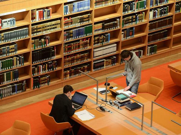 Zwei junge Wissenschaftler arbeiten in einer wissenschaftlichen Bibliothek an ihren Laptops.
