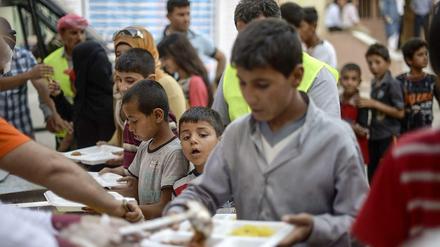 Kinder und Jugendliche stehen an einer Essensausgabe in einem Speisesaal.