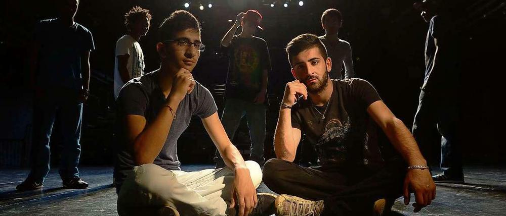 Zwei junge Männer aus Syrien sitzen auf einer Theaterbühne.