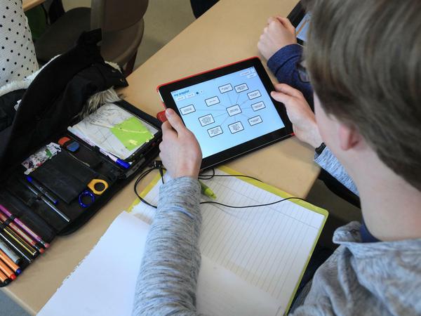 Ein Schüler bearbeitet im Klassenzimmer eine Aufgabe auf einem Tablet.