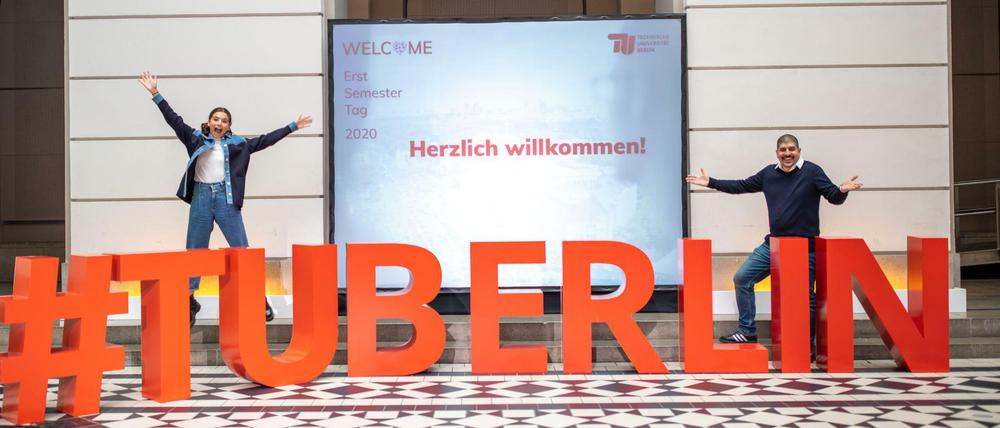 Vor dem plastisch dargestellten Schriftzug #TU Berlin präsentieren eine junge Frau und ein Mann den Erstsemester-Tag.