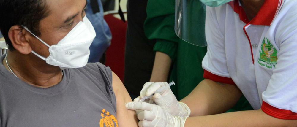 Ein Polizist wird auf der indonesischen Insel Bali gegen Covid-19 geimpft. Indonesien verimpft ein in China entwickeltes Vakzin.