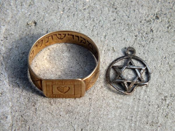 Ein Ring mit einer Gravur in hebräischer Schrift und einem Herzemblem sowie ein Anhänger mit einem Davidstern.
