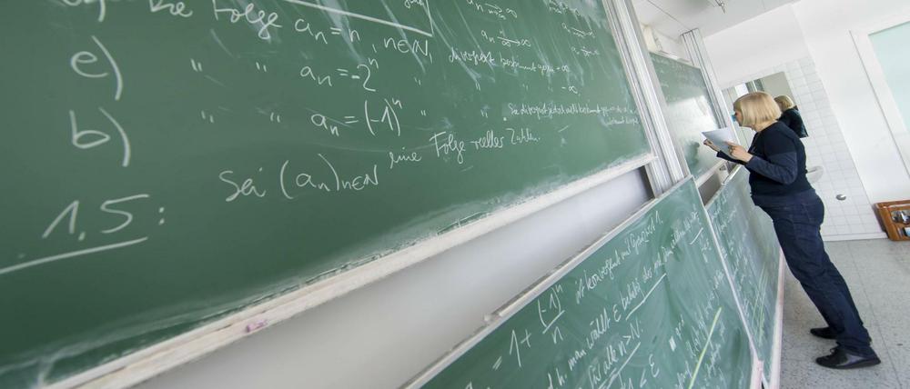 Eine Mathematikerin schreibt in einem Hörsaal Formeln an die Tafel.