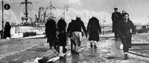 In Leningrad ziehen Frauen während der deutschen Blockade im Zweiten Weltkrieg eine verhüllte Leiche zum Friedhof.